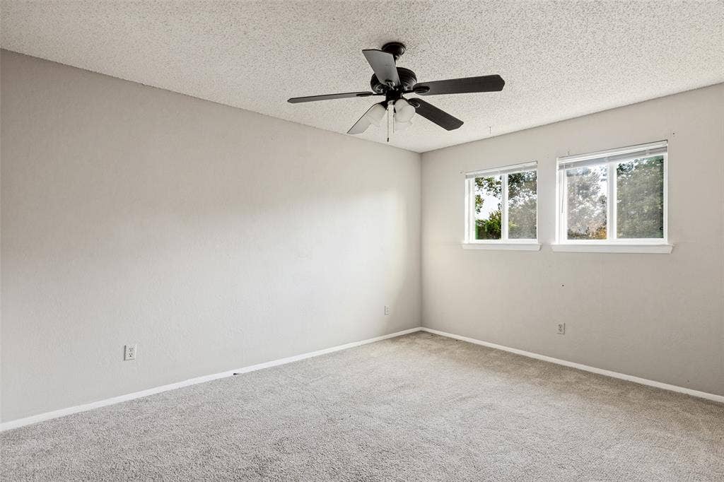 12206 Tyson Cove, #A, Austin, TX 78758 Carpeted room featuring two windows, a ceiling fan with integrated lighting, and neutral wall tones