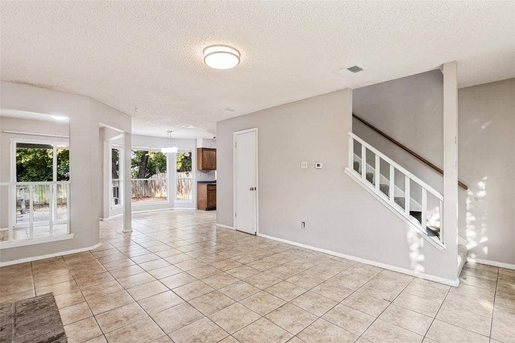 12206 Tyson Cove, #A, Austin, TX 78758 Expansive tiled flooring throughout, staircase with wood handrail, multiple large windows, and recessed lighting