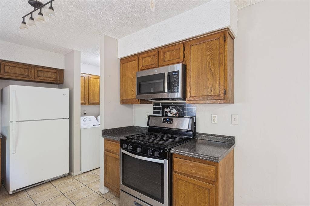12206 Tyson Cove, #A, Austin, TX 78758 Efficient kitchen featuring wood-finish cabinetry, stainless steel gas range with black finish, built-in microwave, and dark countertops