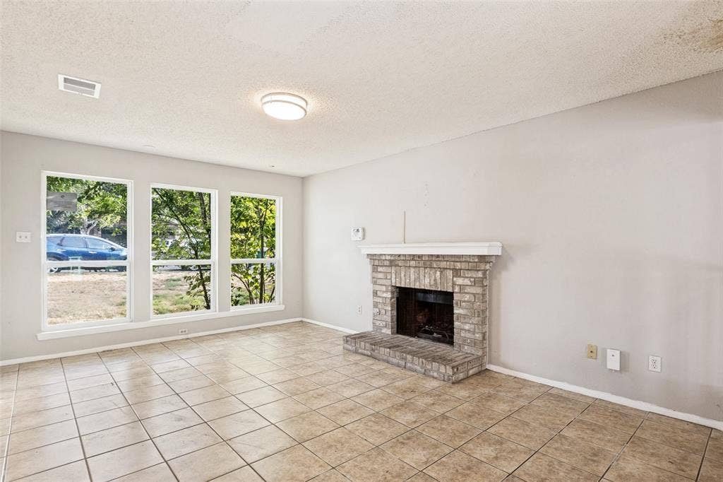 12206 Tyson Cove, #A, Austin, TX 78758 Tile flooring, three large windows, brick fireplace with mantel, and flush-mount ceiling light fixture