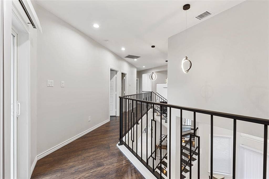 702 Linkcrest Drive, Duncanville, TX 75137 Wood-finish flooring, recessed lighting, contemporary pendant lighting, white walls, and black metal stair railings