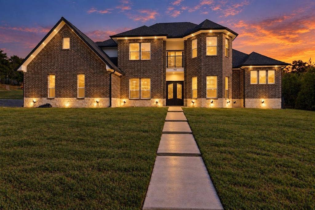 702 Linkcrest Drive, Duncanville, TX 75137 Brick exterior with stone accents, a multi-gabled roofline, and a prominent entry with double doors