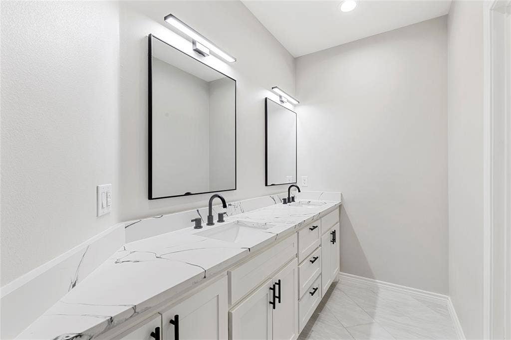 702 Linkcrest Drive, Duncanville, TX 75137 Dual vanities with white cabinetry, black hardware, and integrated sinks