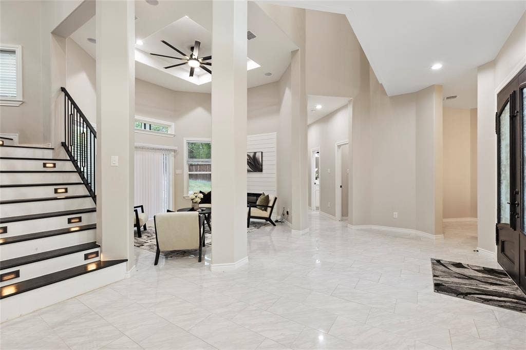 702 Linkcrest Drive, Duncanville, TX 75137 Vaulted ceiling with a ceiling fan, light-colored tile flooring, stairway with accent lighting, white shiplap fireplace, and a dark wood entry door