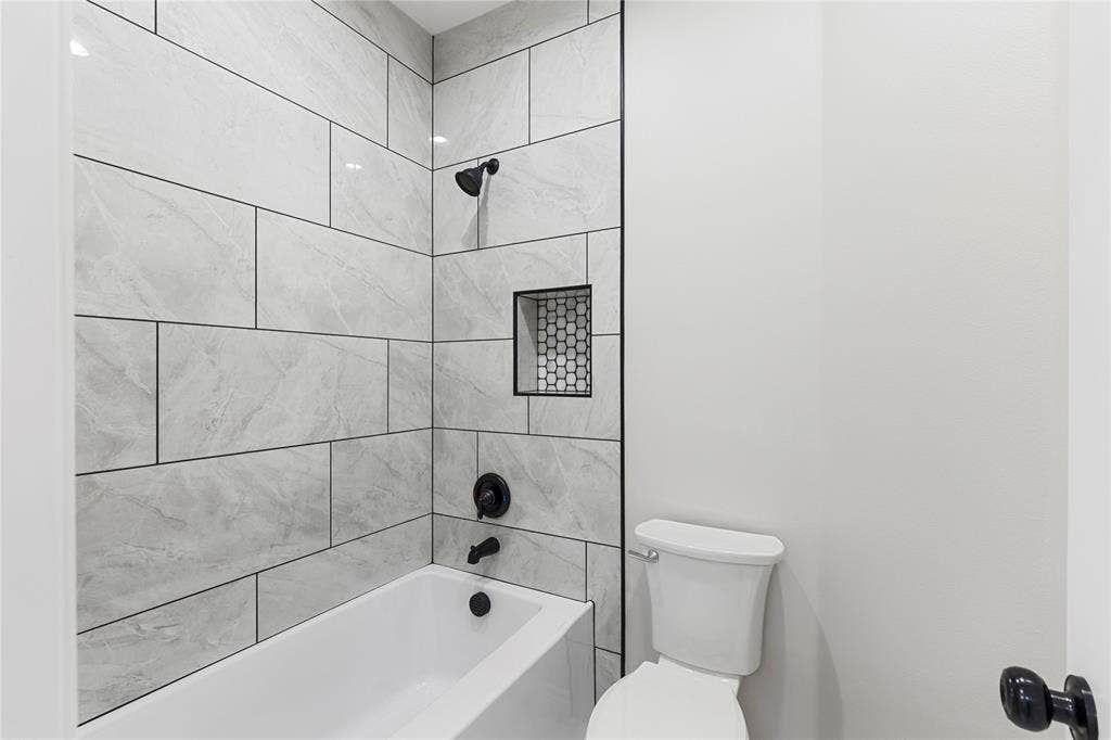 702 Linkcrest Drive, Duncanville, TX 75137 Bathtub with tiled surround, recessed shower niche, and matte black fixtures