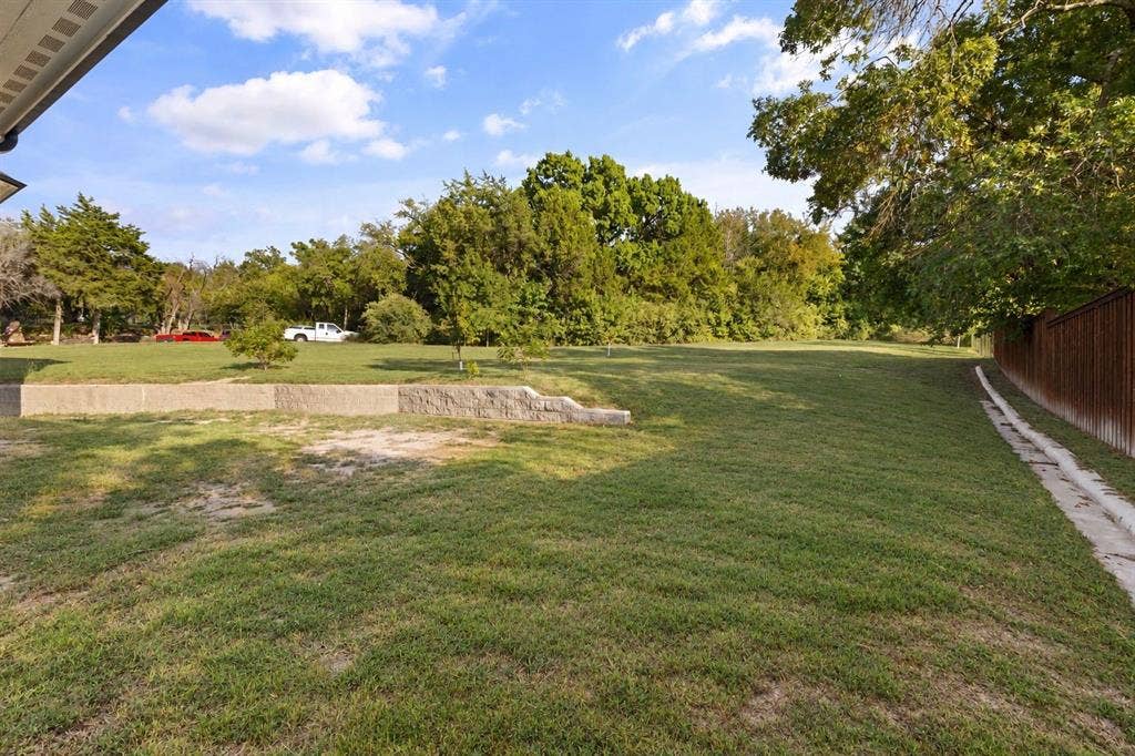 702 Linkcrest Drive, Duncanville, TX 75137 Expansive lawn area with mature trees and a retaining wall