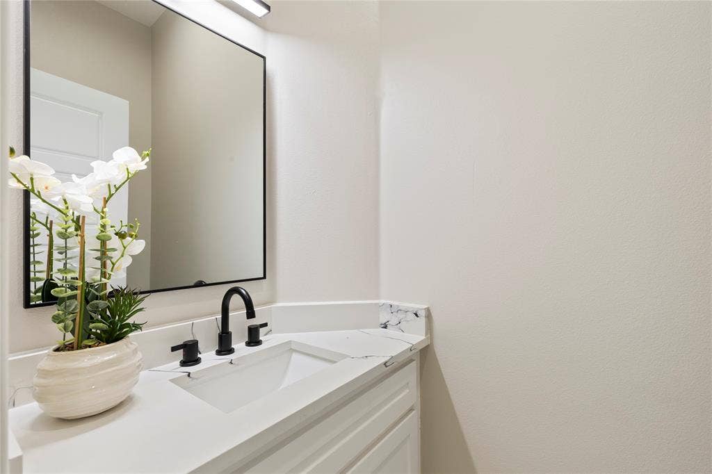 702 Linkcrest Drive, Duncanville, TX 75137 White vanity with a rectangular undermount sink, black matte faucet, and a quartz countertop with a short backsplash