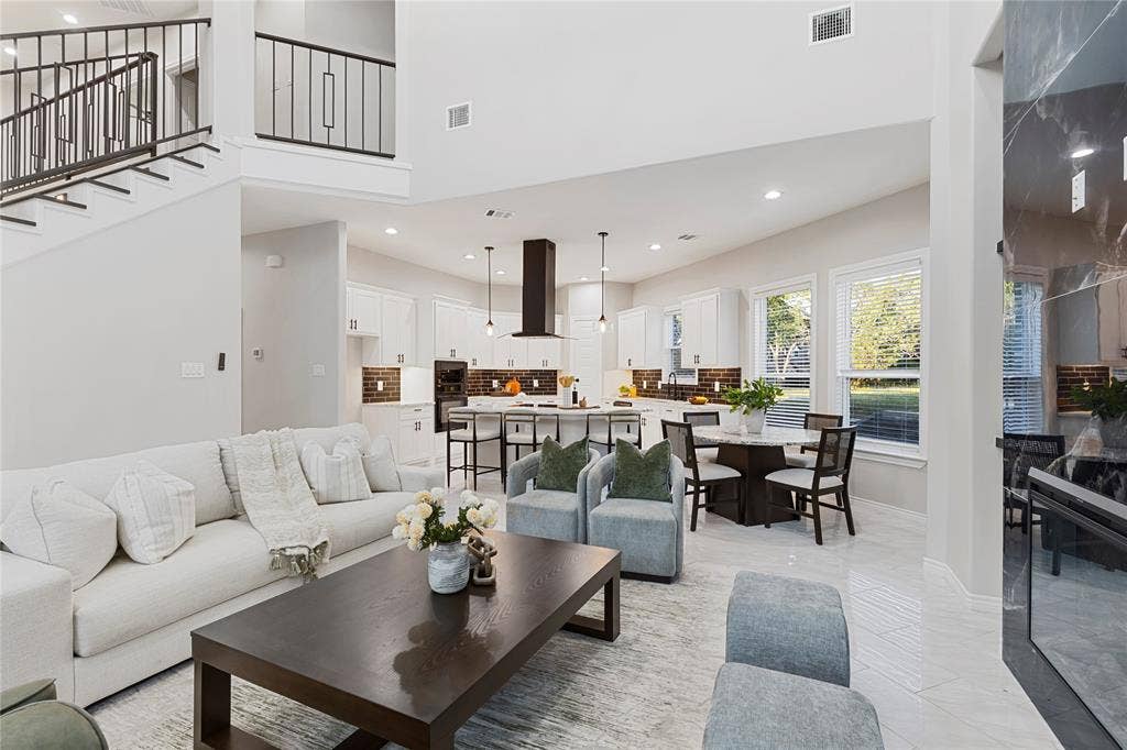 702 Linkcrest Drive, Duncanville, TX 75137 Two-story ceiling, open-concept design, built-in fireplace, large windows, and a kitchen island with seating