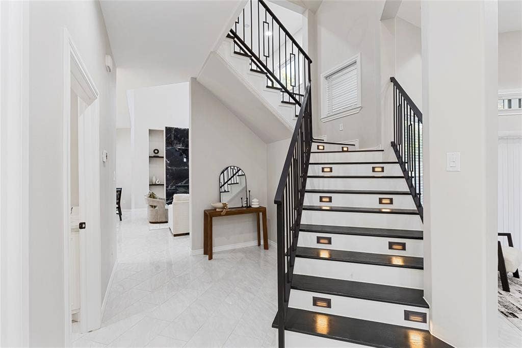 702 Linkcrest Drive, Duncanville, TX 75137 Staircase featuring dark treads, white risers, and contemporary black metal railings