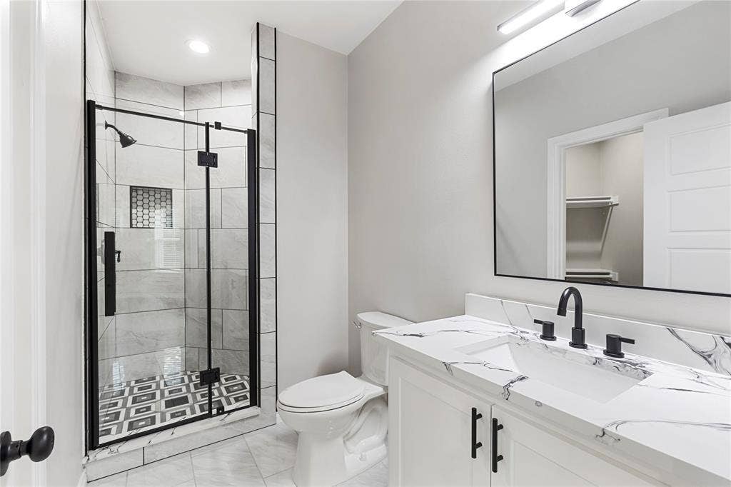 702 Linkcrest Drive, Duncanville, TX 75137 Glass-enclosed shower with black-framed door and patterned tile flooring