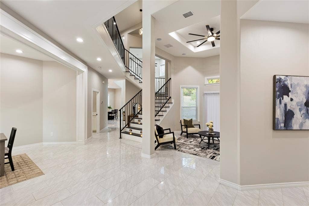 702 Linkcrest Drive, Duncanville, TX 75137 Spacious open-concept interior featuring light-toned flooring, a grand staircase with wrought-iron railings, a recessed ceiling with a fan, and recessed lighting throughout