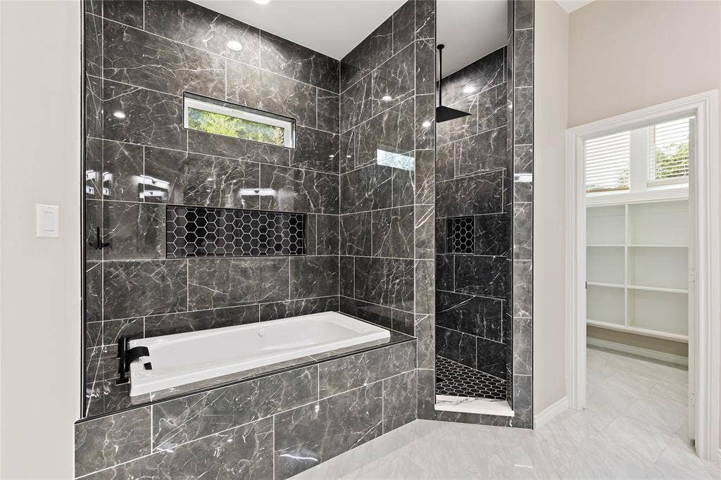 702 Linkcrest Drive, Duncanville, TX 75137 Full-height dark tile surround with integrated bathtub, built-in shower, black fixtures, and recessed lighting
