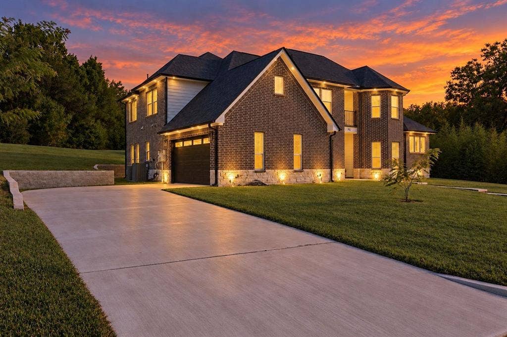 702 Linkcrest Drive, Duncanville, TX 75137 Brick and siding exterior with stone accents, concrete driveway, attached garage, and exterior accent lighting