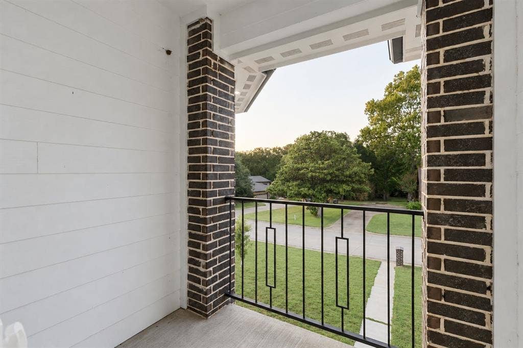 702 Linkcrest Drive, Duncanville, TX 75137 Balcony featuring dark brick columns, white horizontal siding, a black metal railing, and a concrete floor