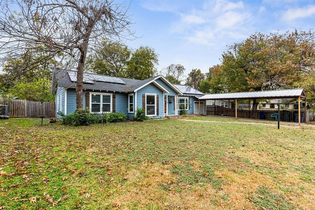 4205 Fort Avenue, Waco, TX 76710 Blue exterior siding with white trim, solar panels, a covered carport, and a wood privacy fence