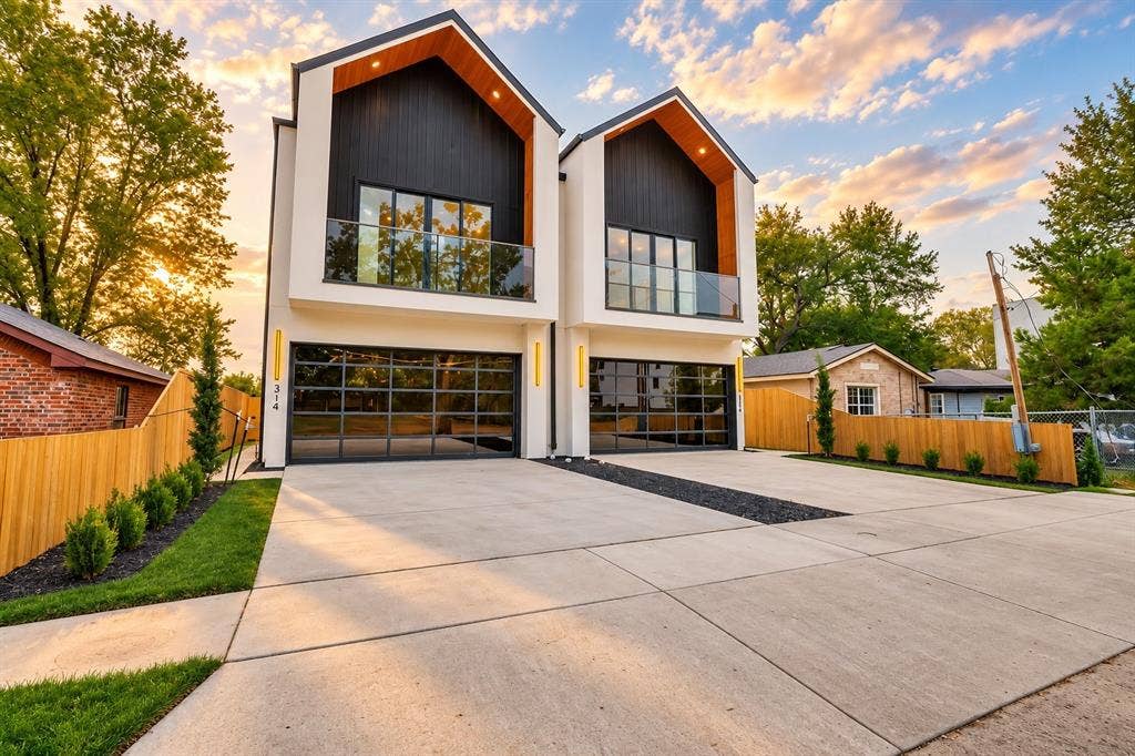 314 Avenue L, Dallas, TX 75203 Modern exterior with a white and black facade, gabled roof accents with wood-finish soffits, full-light garage doors, and glass balcony railings