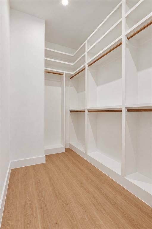 314 Avenue L, Dallas, TX 75203 Walk-in closet featuring extensive built-in shelving, multiple hanging rods, recessed ceiling lighting, and wood-finish flooring