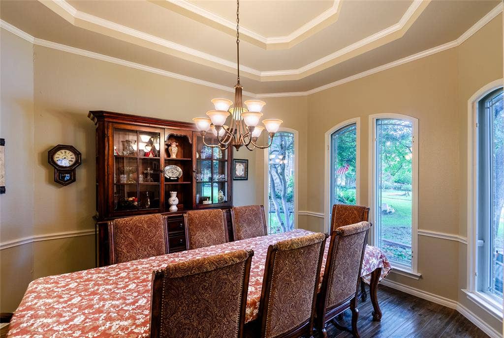 4009 Wilshire Court, Plano, TX 75023 Dining space featuring tray ceiling with crown molding, dark wood-finish flooring, and multiple arched windows