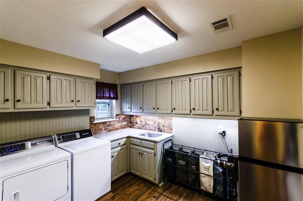4009 Wilshire Court, Plano, TX 75023 Utility room featuring wood-finish flooring, beadboard wainscoting, light-toned cabinetry, and a corner sink with brick-style backsplash