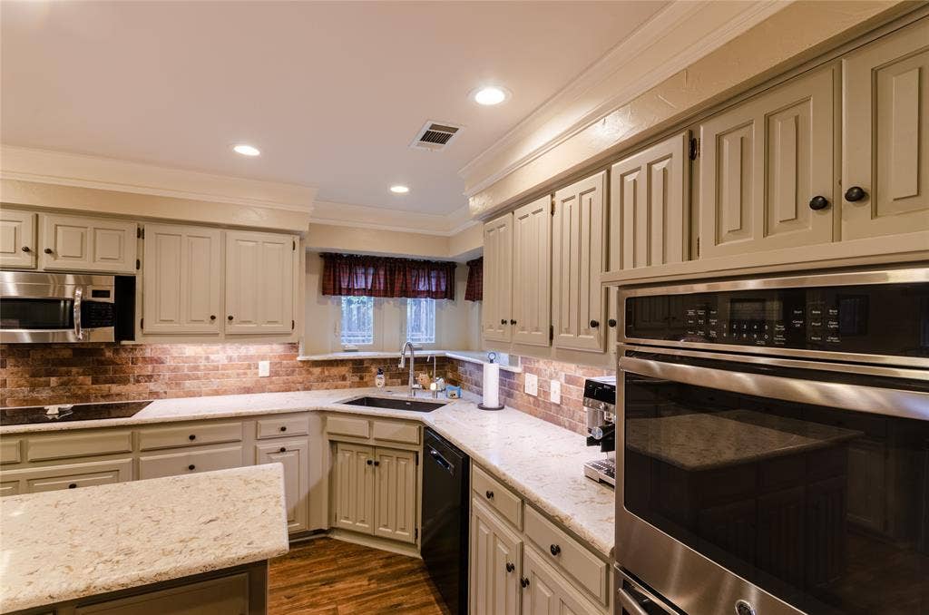 4009 Wilshire Court, Plano, TX 75023 Kitchen featuring light-toned cabinetry, light-hued countertops, a brick-patterned backsplash, stainless steel appliances, and recessed lighting