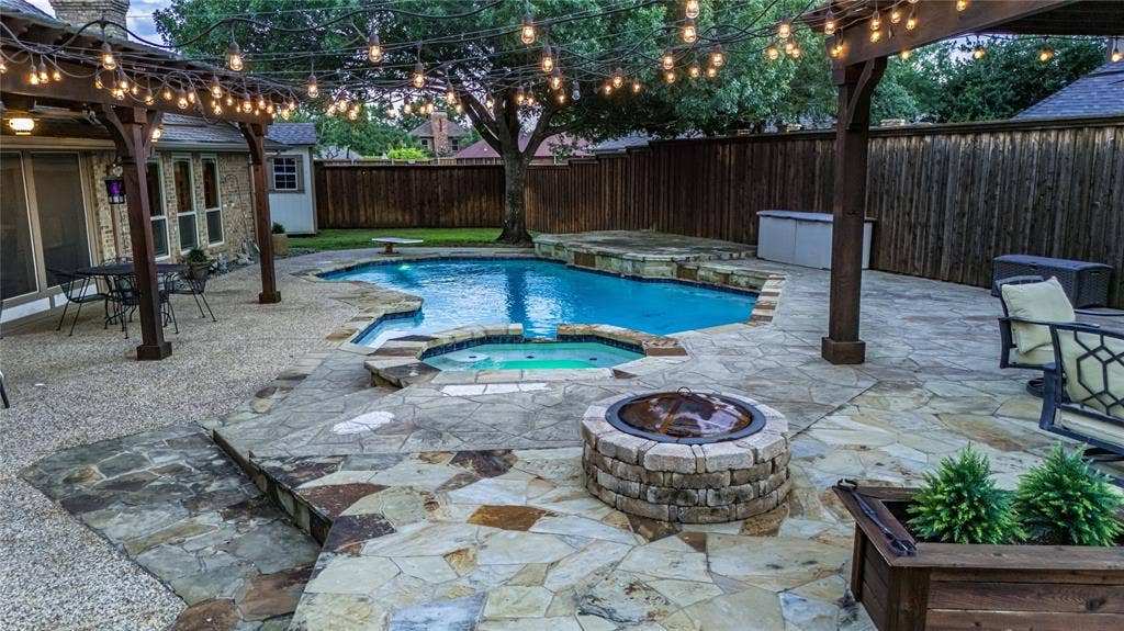 4009 Wilshire Court, Plano, TX 75023 Expansive stone patio featuring a built-in swimming pool and integrated spa