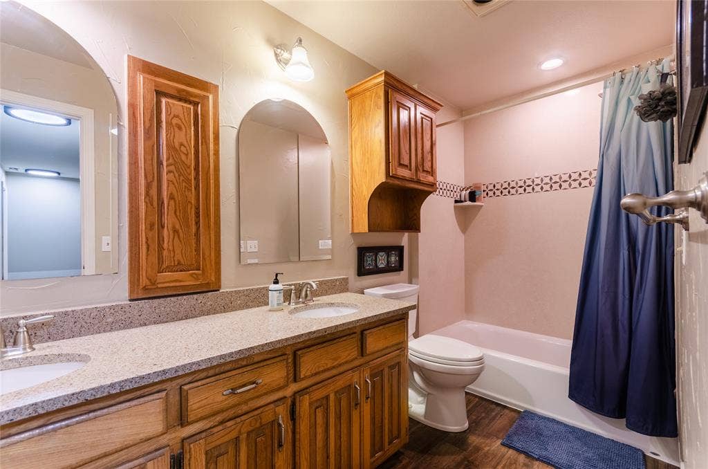 4009 Wilshire Court, Plano, TX 75023 Bathroom featuring a double vanity with light-toned countertops and wood-finish cabinetry