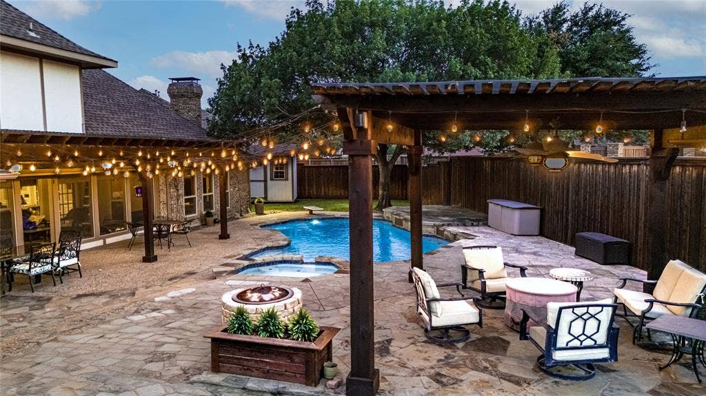 4009 Wilshire Court, Plano, TX 75023 Expansive flagstone patio featuring a built-in fire pit, a free-form swimming pool with an integrated spa, and multiple pergolas