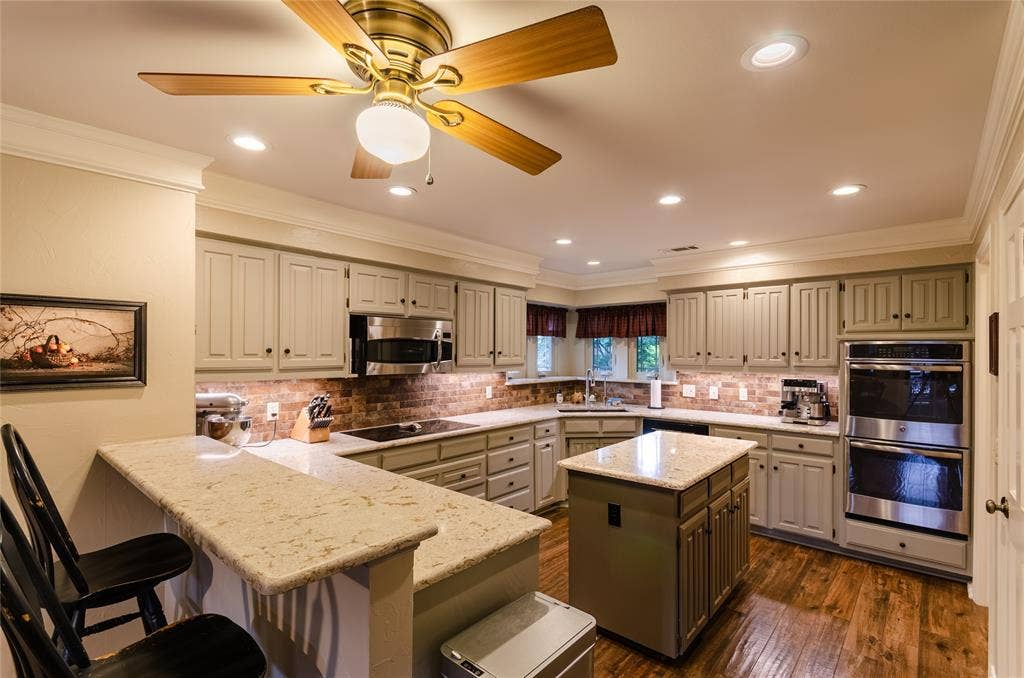 4009 Wilshire Court, Plano, TX 75023 Kitchen featuring recessed lighting, a central island, wood-finish flooring, light-toned cabinetry, and stainless steel double wall ovens