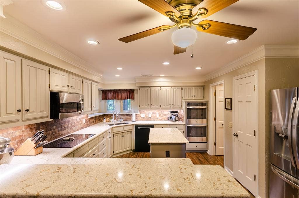 4009 Wilshire Court, Plano, TX 75023 Kitchen featuring extensive light-toned cabinetry, a spacious U-shaped countertop, a central island, and stainless steel appliances