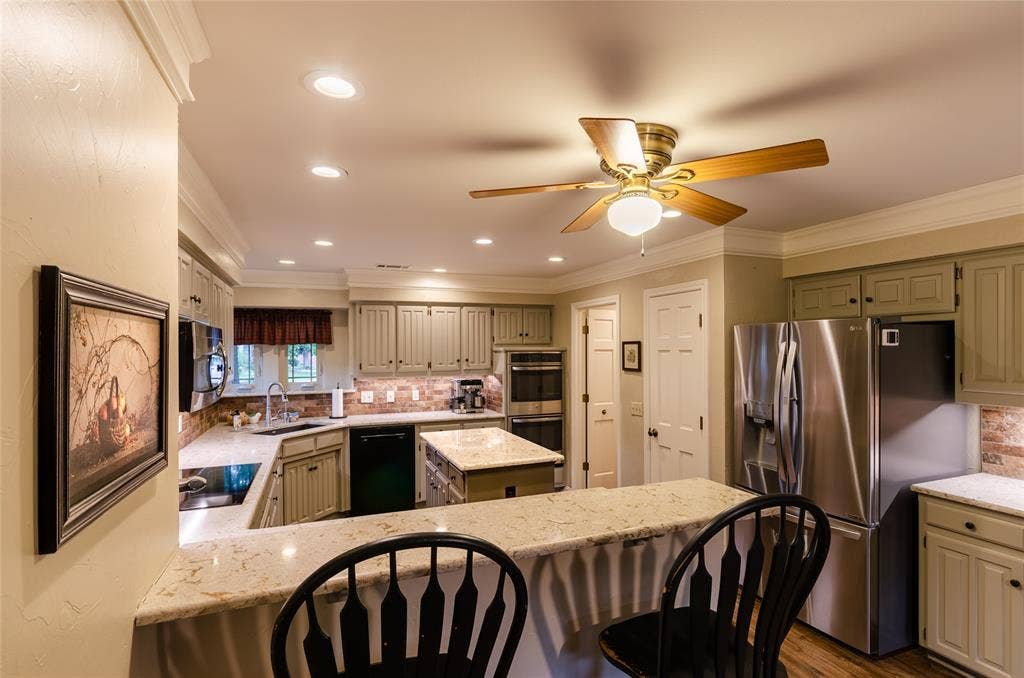4009 Wilshire Court, Plano, TX 75023 Kitchen featuring light-toned cabinetry, stainless steel appliances, and a central island with a breakfast bar