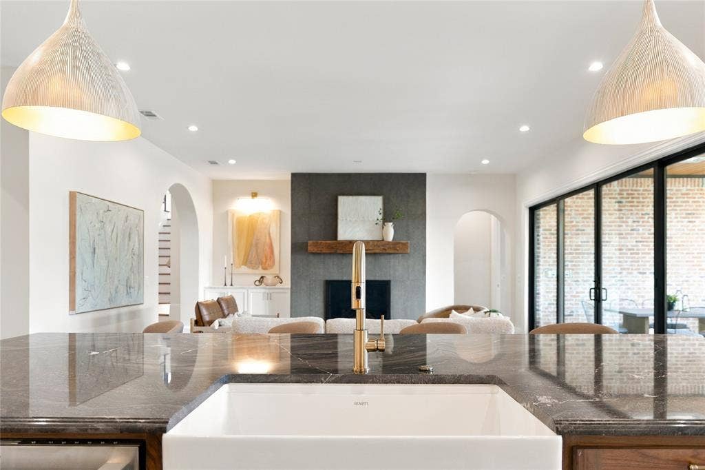 3368 Dorado Beach Drive, Farmers Branch, TX 75234 Kitchen island featuring a white apron front sink, brass-finish faucet, and dark stone countertop