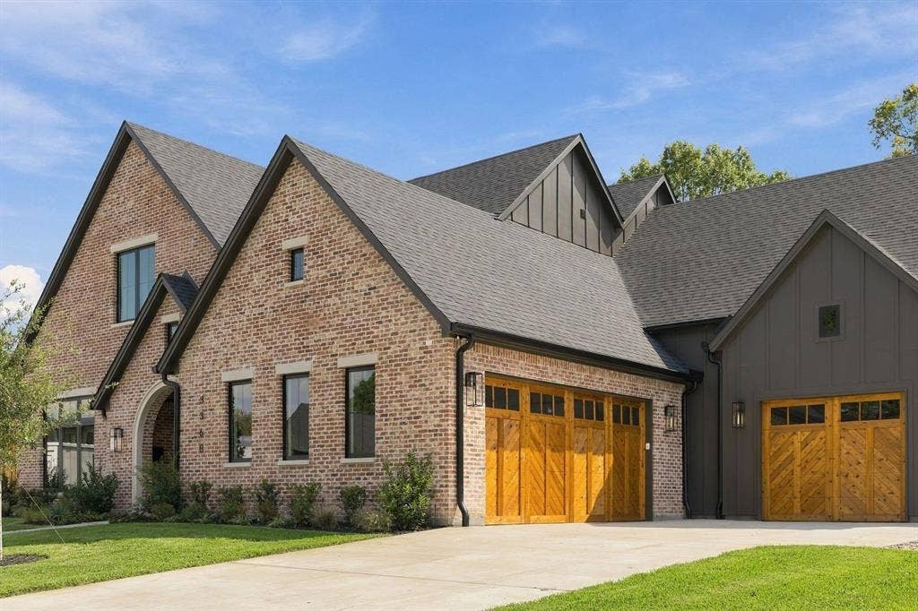 3368 Dorado Beach Drive, Farmers Branch, TX 75234 Brick and vertical siding exterior with gabled roofs, multiple wooden garage doors, and a concrete driveway