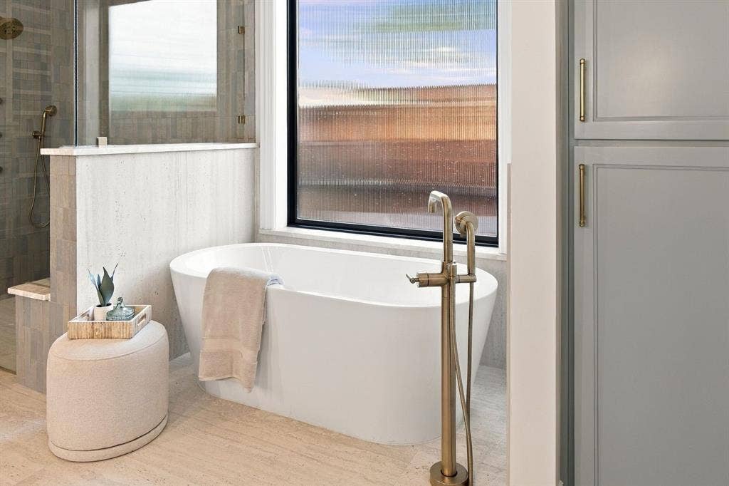 3368 Dorado Beach Drive, Farmers Branch, TX 75234 Freestanding soaking tub with a floor-mounted brass faucet, tile flooring, and integrated shower with glass enclosure