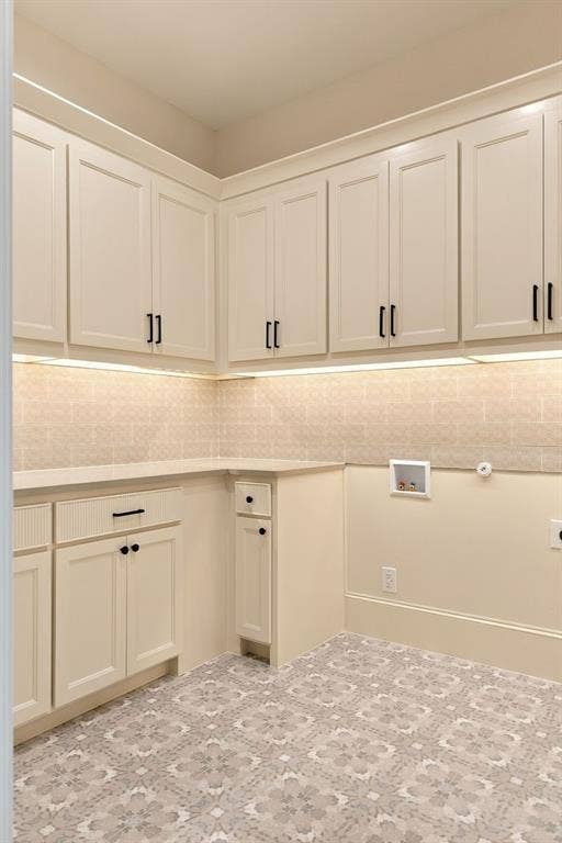 3368 Dorado Beach Drive, Farmers Branch, TX 75234 Extensive built-in cabinetry with matte black hardware, integrated lighting, solid surface countertops, patterned floor tiles, and a tiled backsplash