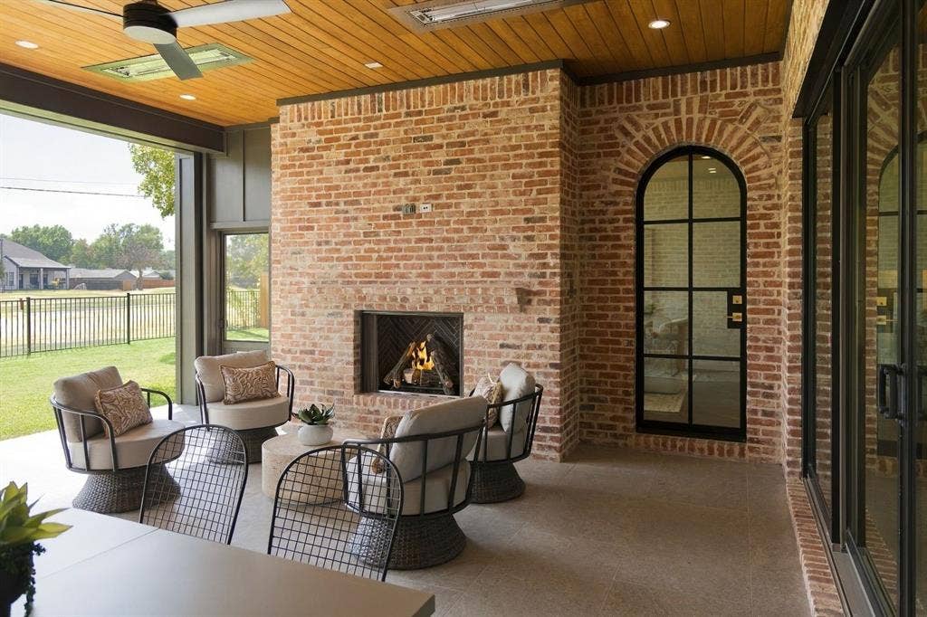 3368 Dorado Beach Drive, Farmers Branch, TX 75234 Covered patio featuring a brick fireplace, wood-plank ceiling, and a black wrought iron arched door