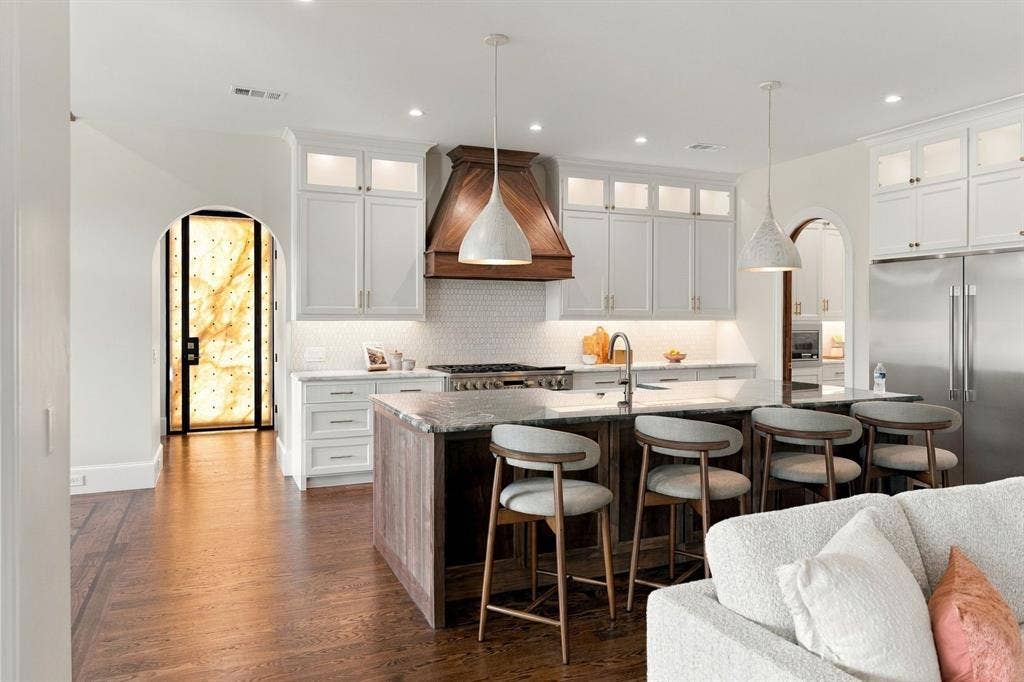 3368 Dorado Beach Drive, Farmers Branch, TX 75234 Gourmet kitchen with wood-finish flooring, white cabinetry, a wood range hood, a kitchen island with a stone countertop, and stainless steel appliances