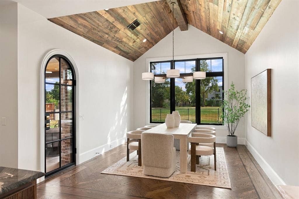 3368 Dorado Beach Drive, Farmers Branch, TX 75234 Vaulted ceiling with wood-finish planks, large black-framed window, arched glass-panel door, and herringbone wood-finish flooring