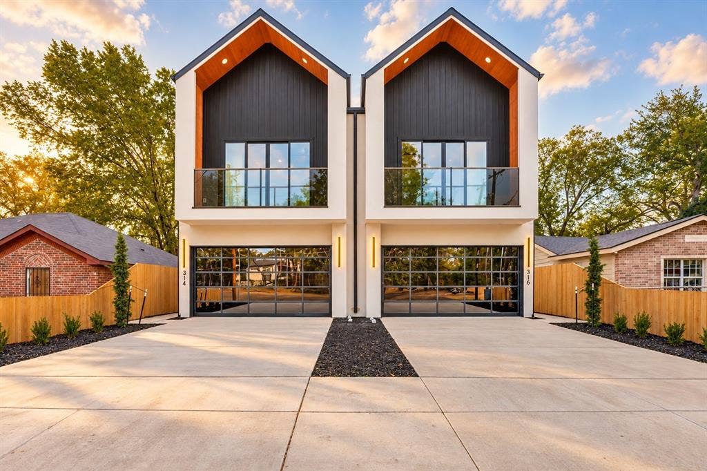 314 & 316 Avenue L, Dallas, TX 75203 Modern duplex featuring a white stucco and black siding exterior, vaulted wood-finish porch ceilings, glass panel garage doors, and a concrete driveway