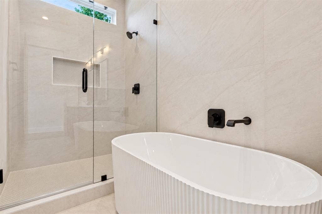 314 & 316 Avenue L, Dallas, TX 75203 Freestanding soaking tub, glass-enclosed shower with a recessed niche, and matte black fixtures