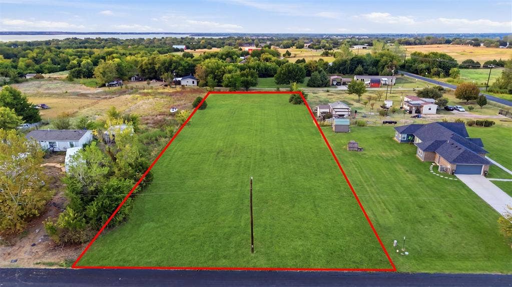 000 CR-760, Nevada, TX 75173 Expansive lot featuring a manicured lawn, established landscaping, and a distant water body