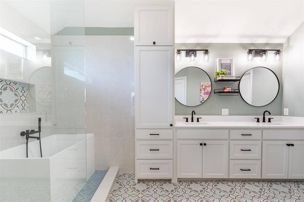 En-suite bath with dual sinks and linen cabinetry.