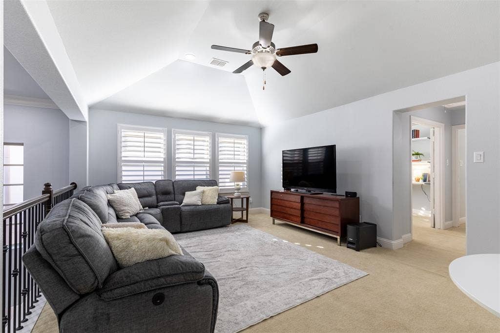 Spacious game room with vaulted ceiling and plantation shutters.