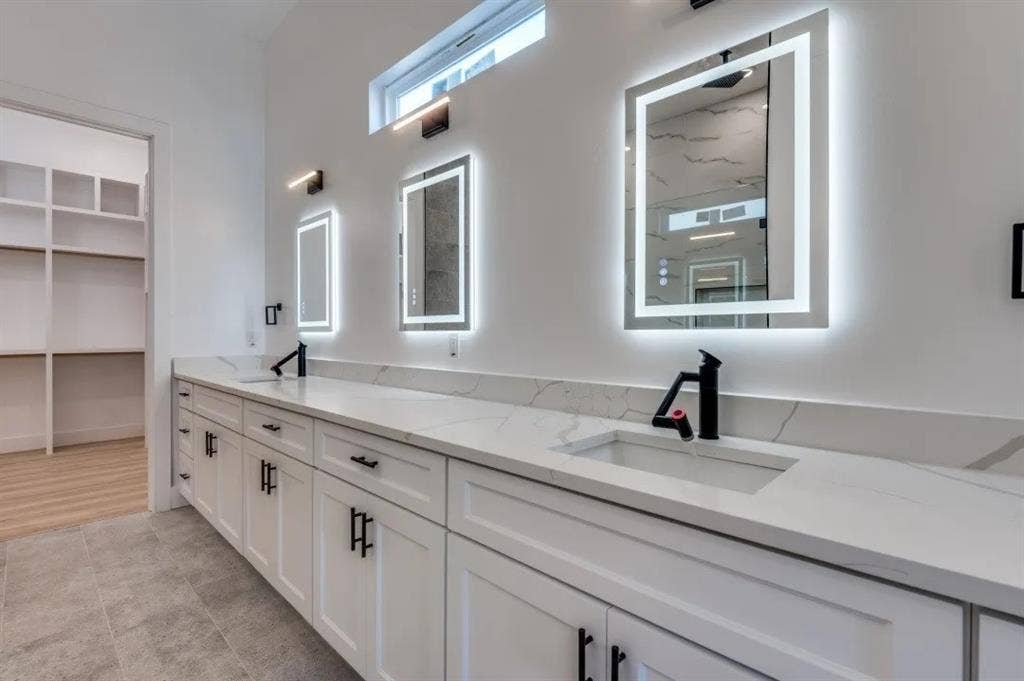 2802 Guymon Street, Dallas, TX 75212 Dual vanity with white cabinetry and black hardware, stone-finish countertop, integrated rectangular sinks, and backlit mirrors