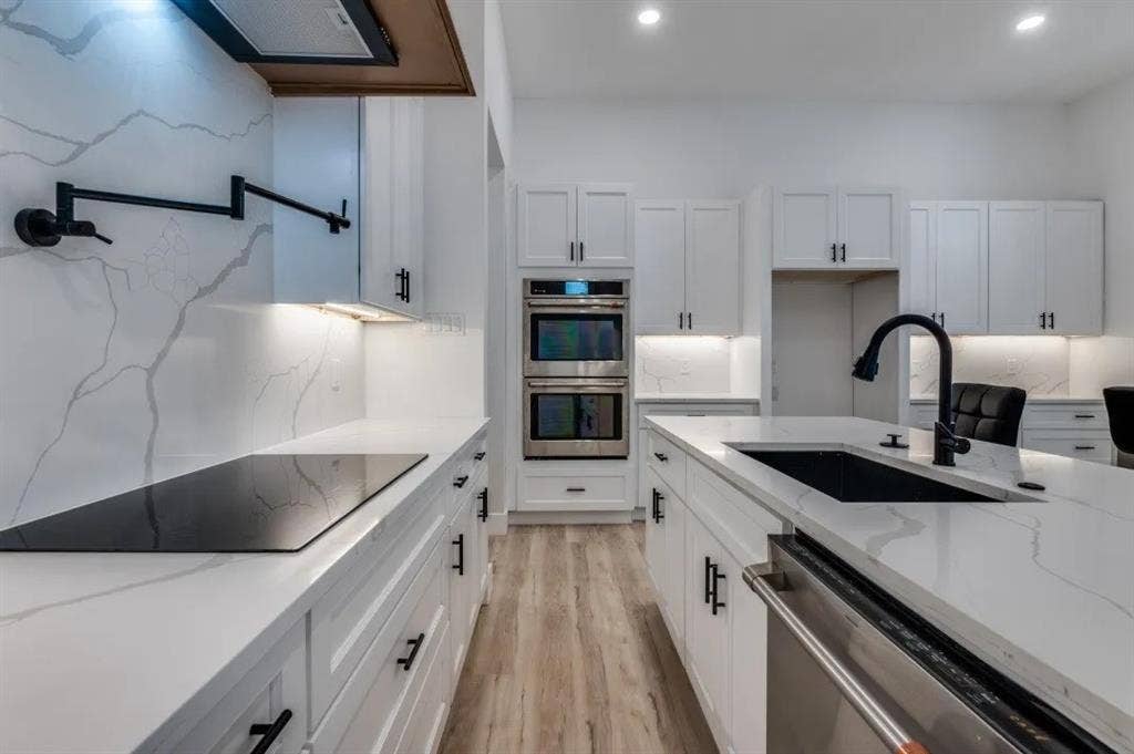 2802 Guymon Street, Dallas, TX 75212 Contemporary kitchen featuring white cabinetry, light-toned countertops, a built-in cooktop, stainless steel double ovens, and a kitchen island with an undermount sink