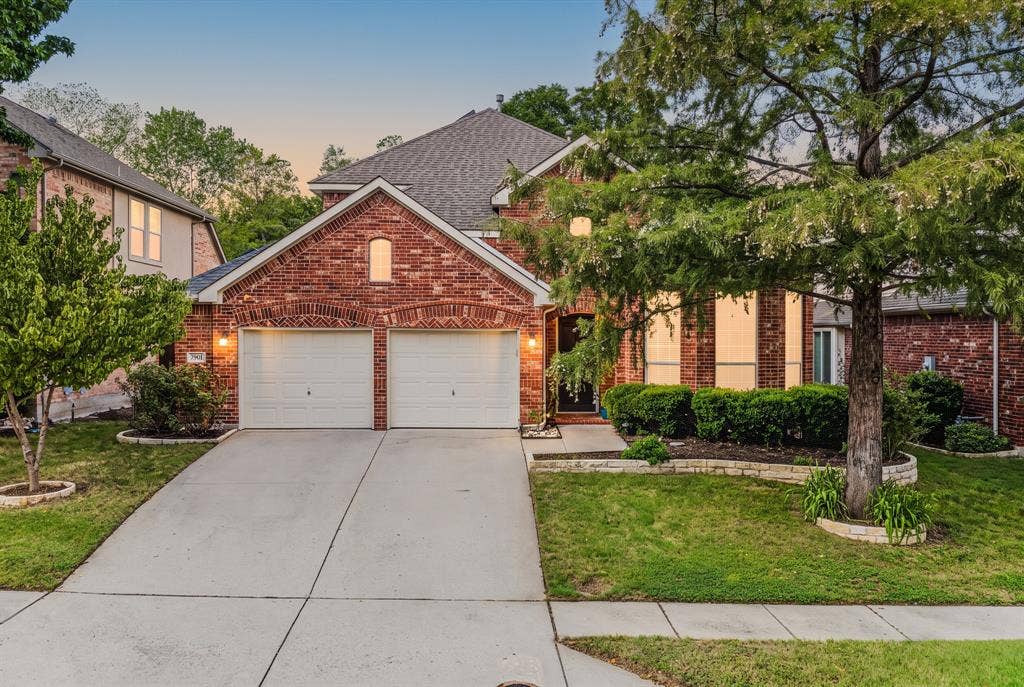 1905 Canyon Wren Drive, McKinney, TX 75071 Red brick exterior with garage doors, shingled roof, mature landscaping, and a concrete driveway