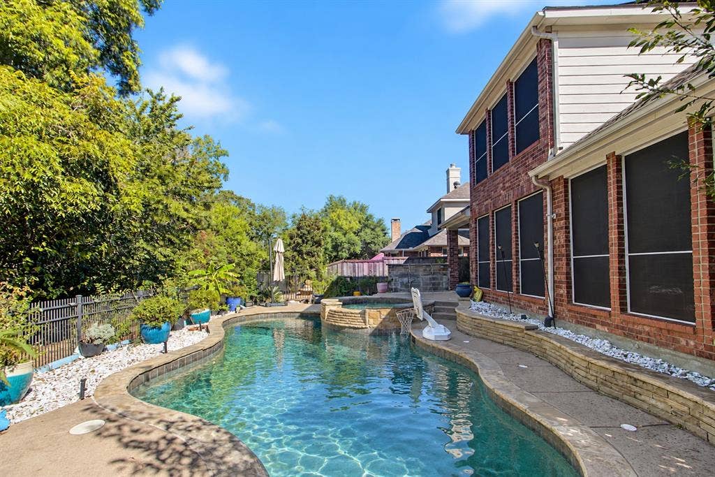 1905 Canyon Wren Drive, McKinney, TX 75071 Private backyard retreat with greenbelt views, a pool and raised spa, expansive concrete decking, and mature landscaping. Photo taken right after a few days of heavy thunderstorms and rain while the pool was undergoing maintenance. Water shown in the pool and spa has been digitally added.
