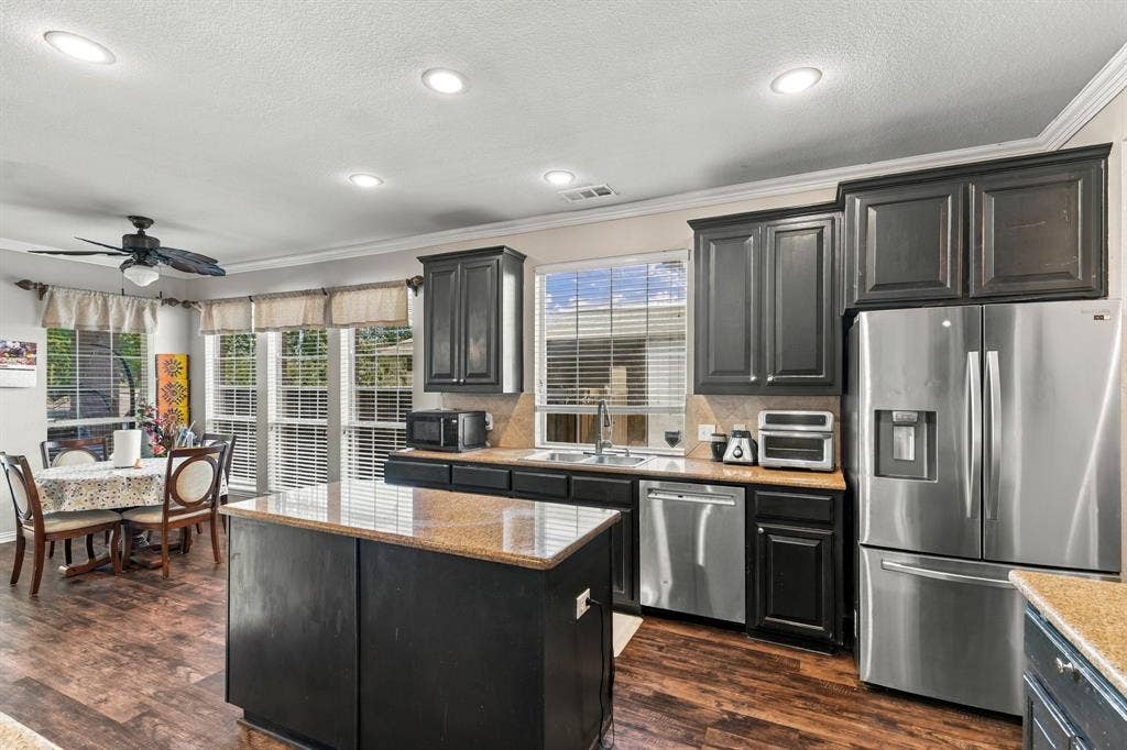 1905 Canyon Wren Drive, McKinney, TX 75071 Kitchen with dark wood-finish cabinetry, stainless steel appliances, and a central island