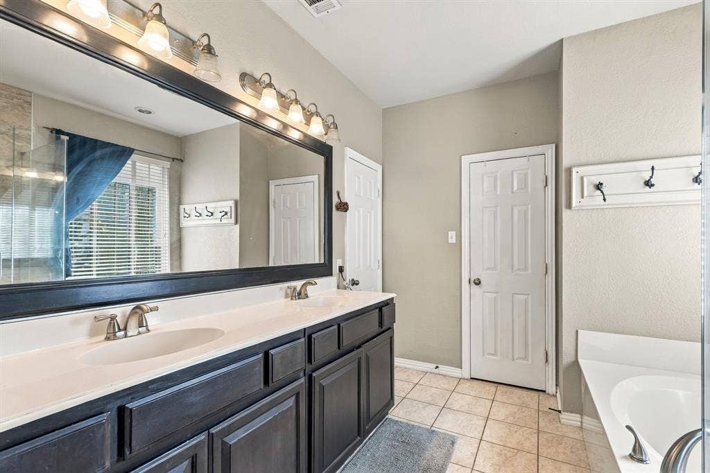 1905 Canyon Wren Drive, McKinney, TX 75071 Master bath with dual-sinks, soaking tub, separate shower area base cabinetry with ample storage, and a large framed mirror