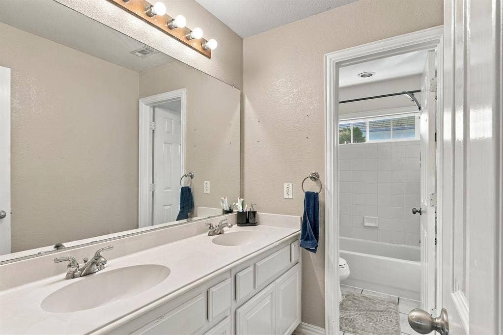 1905 Canyon Wren Drive, McKinney, TX 75071 Upstairs full bath with dual sinks, light fixture, large wall-mounted mirror