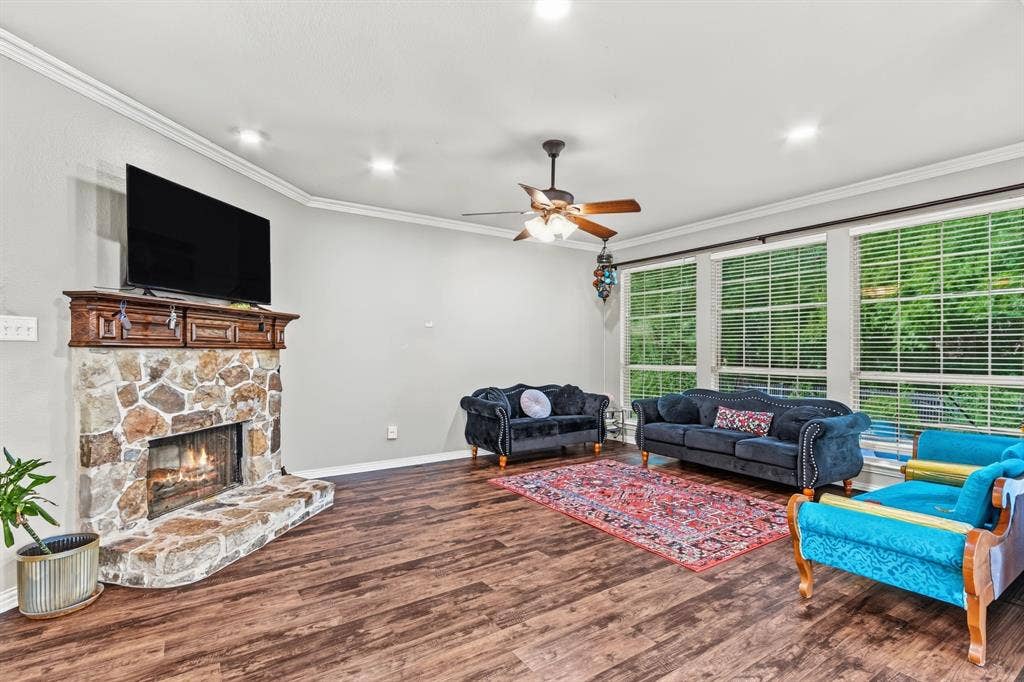 1905 Canyon Wren Drive, McKinney, TX 75071 Wood-style flooring, stone-clad fireplace with wood mantel, multiple windows with blinds, ceiling fan with integrated lighting, recessed ceiling lighting